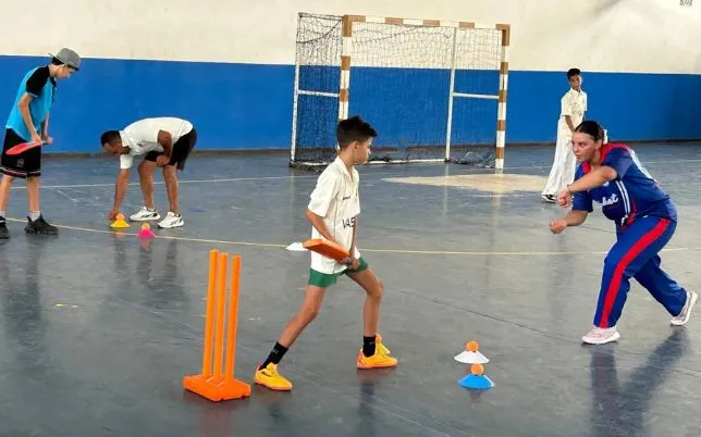 cricket in morocco a young batter practises beside orange stumps with a coach during indoor training